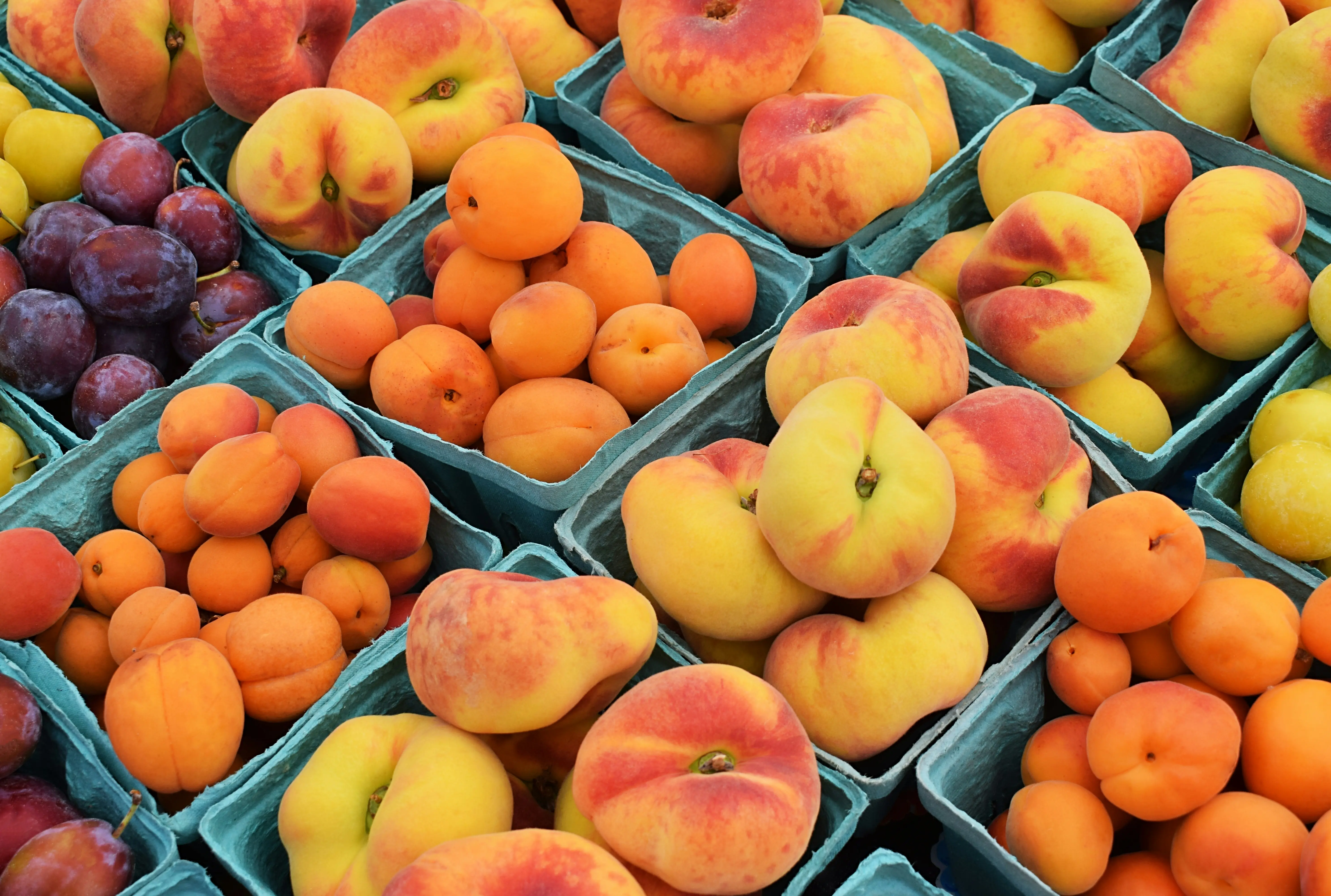 Assorted fresh peaches and stone fruits at farmers market for making peach persimmon smoothies