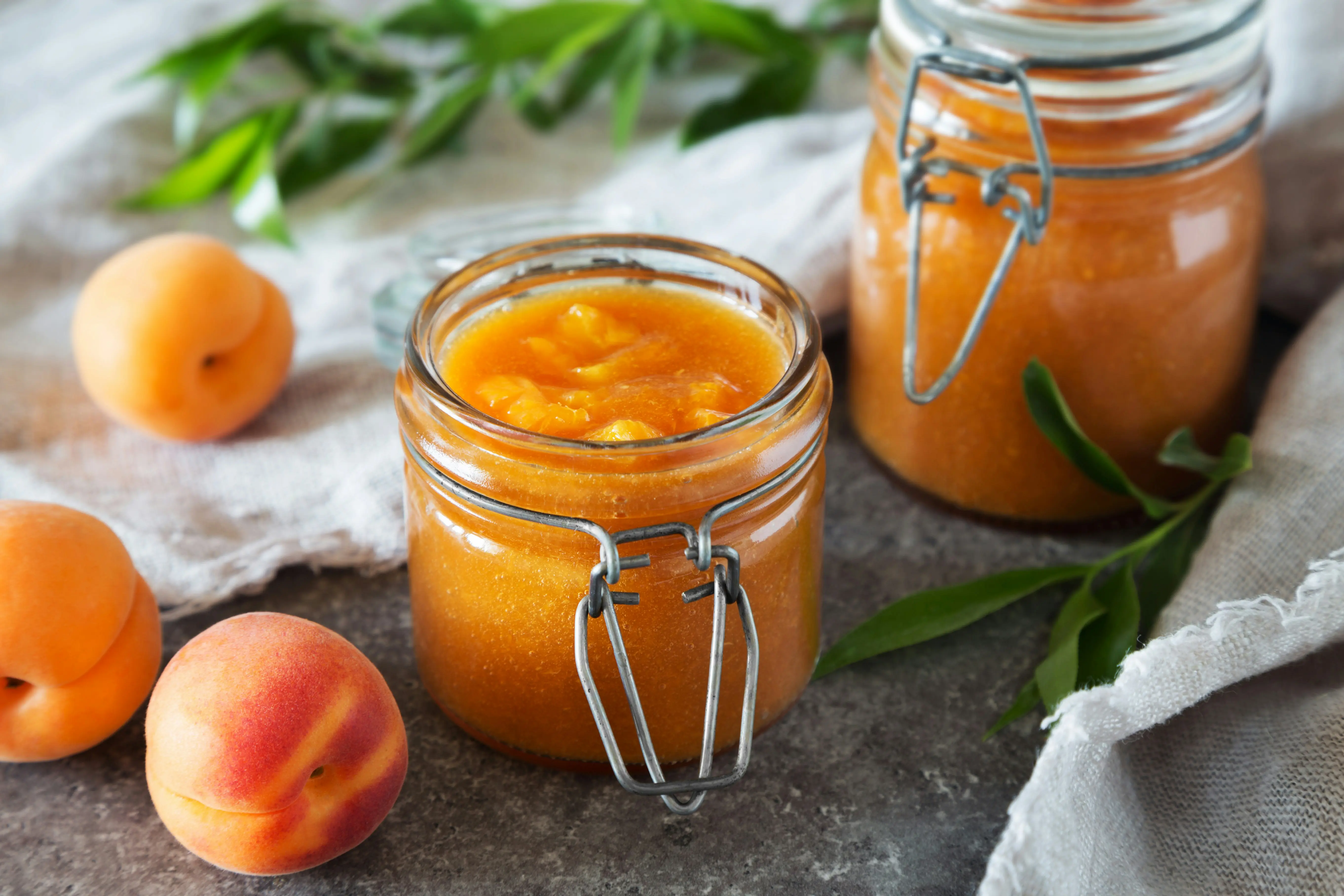 Homemade peach persimmon smoothie in glass jars with fresh peach fruit, thick smoothie texture